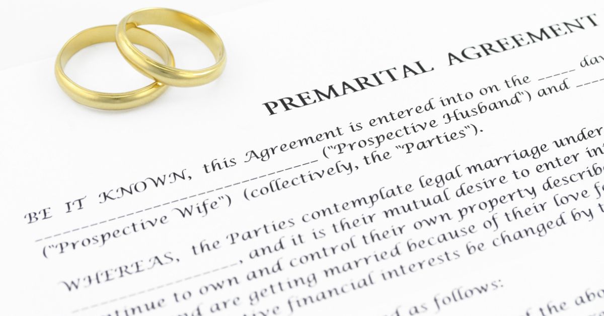 Prenuptial agreement document with two wedding bands on top